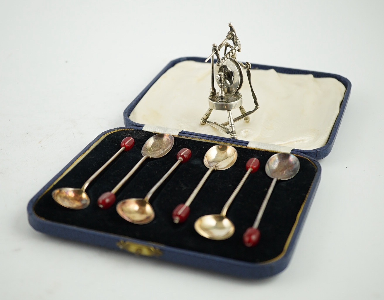 An Edwardian silver miniature articulated model spinning wheel, by Deakin and Francis Ltd, Birmingham 1905, 8.5cm and a cased set of coffee spoons, Sheffield 1936, with ‘bean’ terminals. Condition - fair